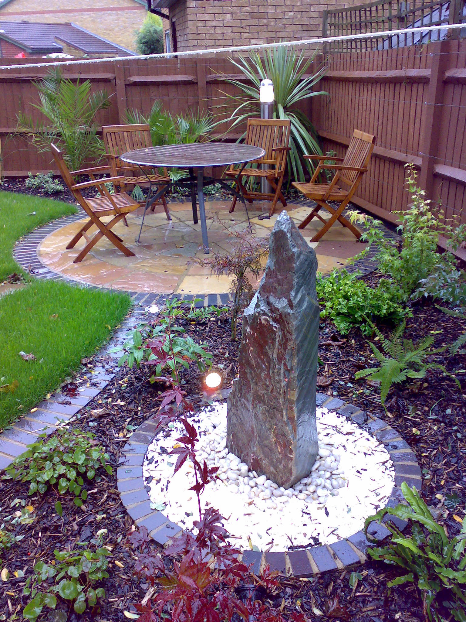 View into the garden looking at the circular seating area with water feature in the foreground